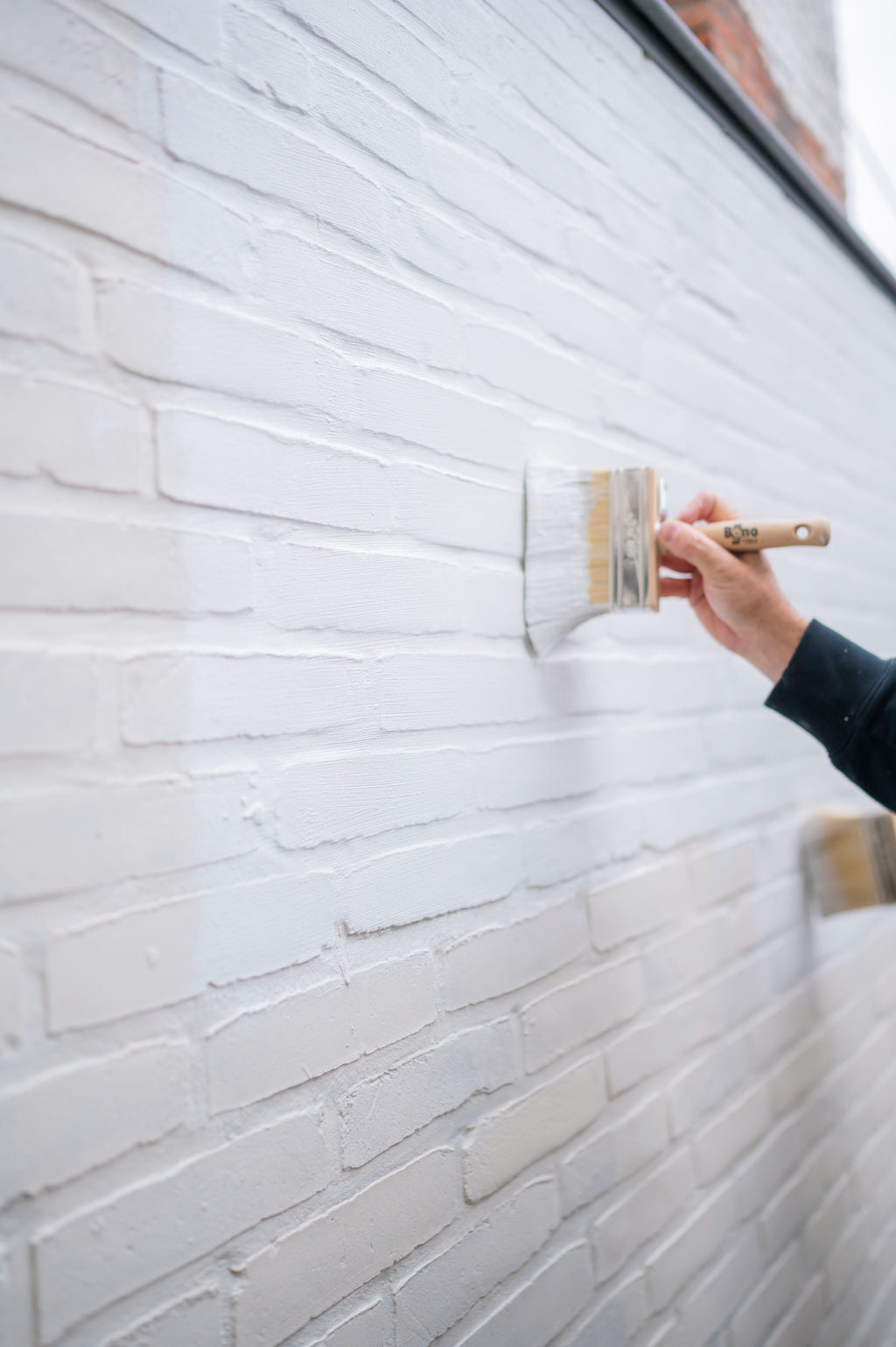 Het aanbrengen van primer muur buiten met een blokborstel