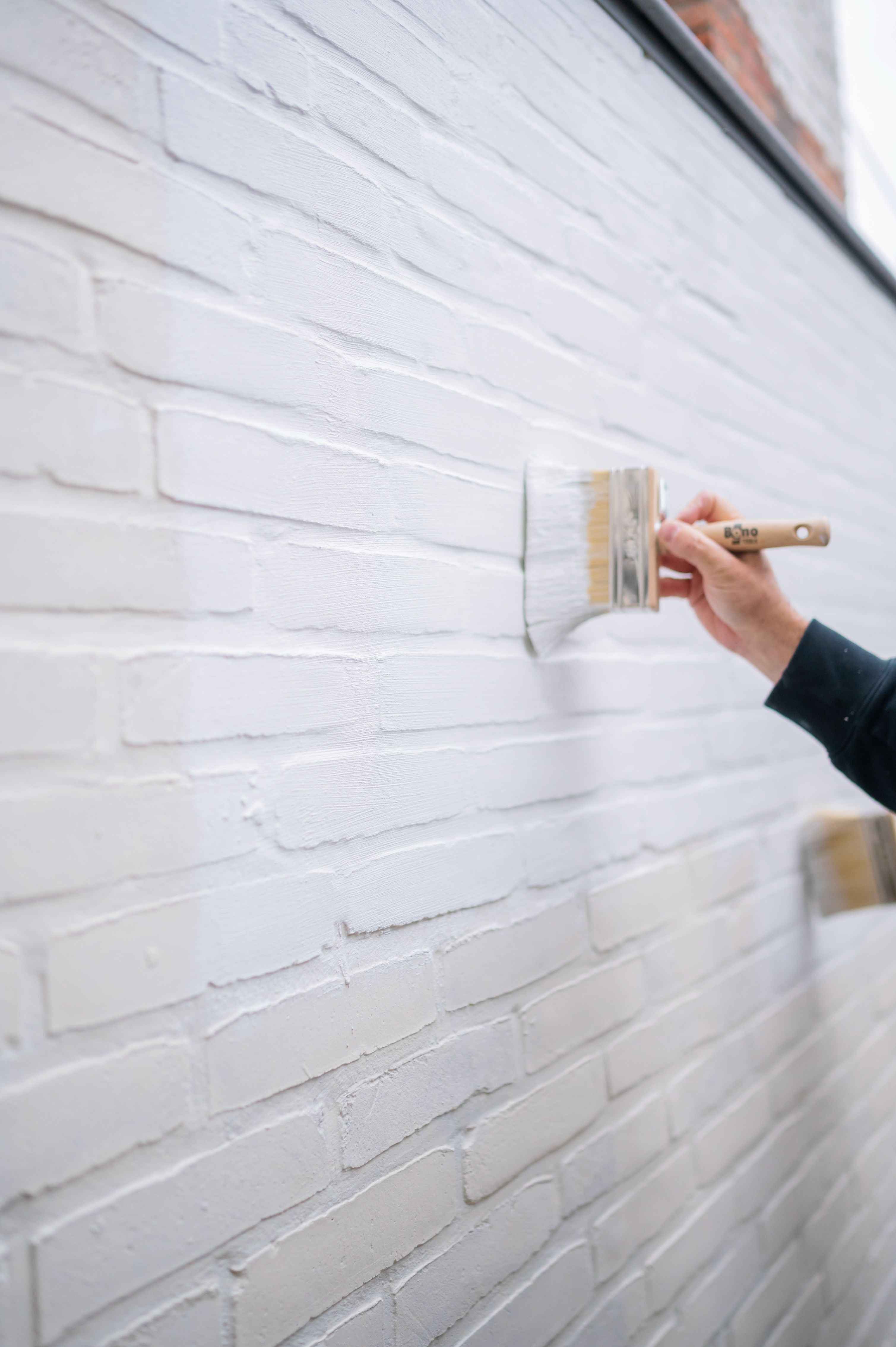 Het aanbrengen van primer muur buiten met een blokborstel